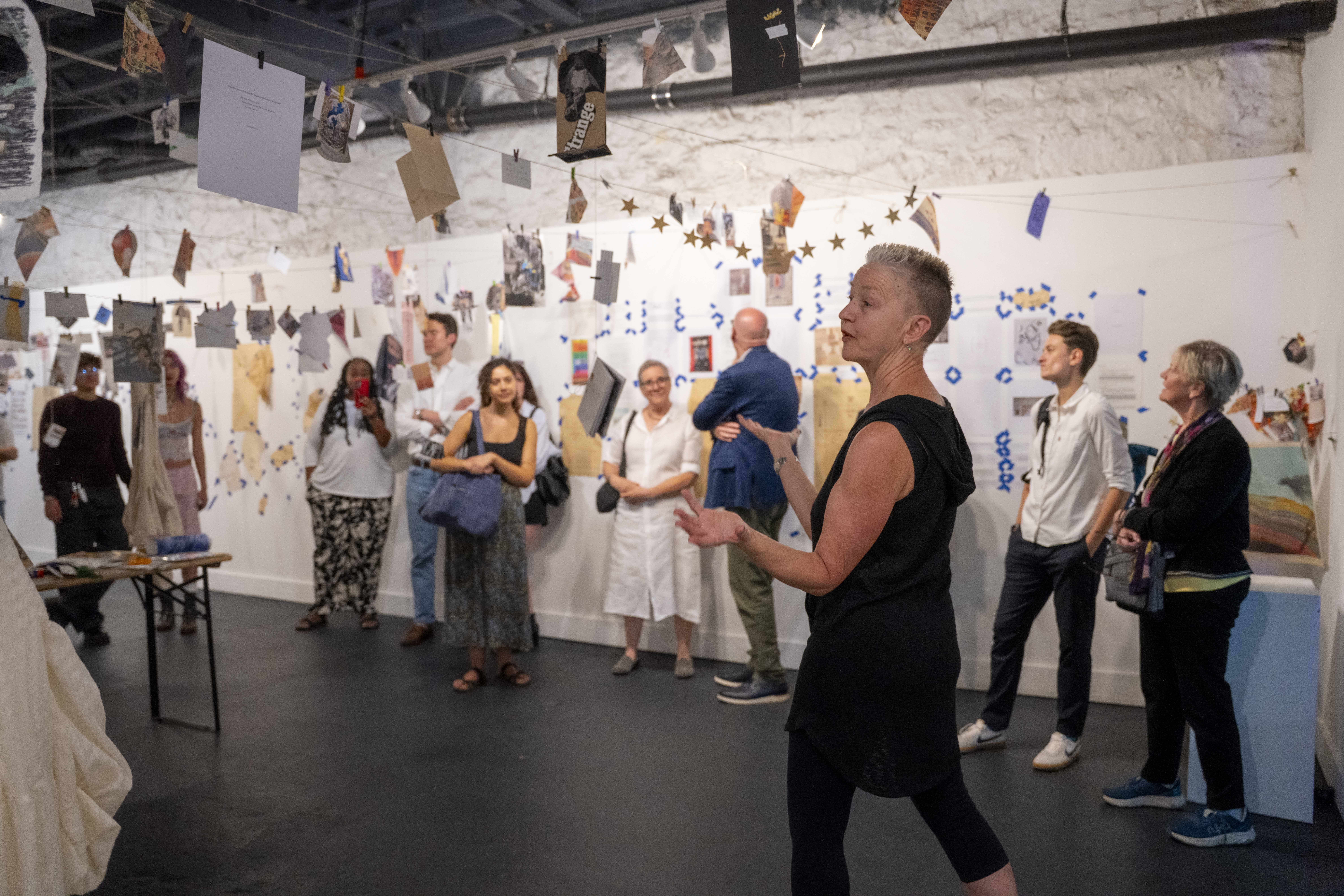 A woman leading a talk in an art exhibit studio
