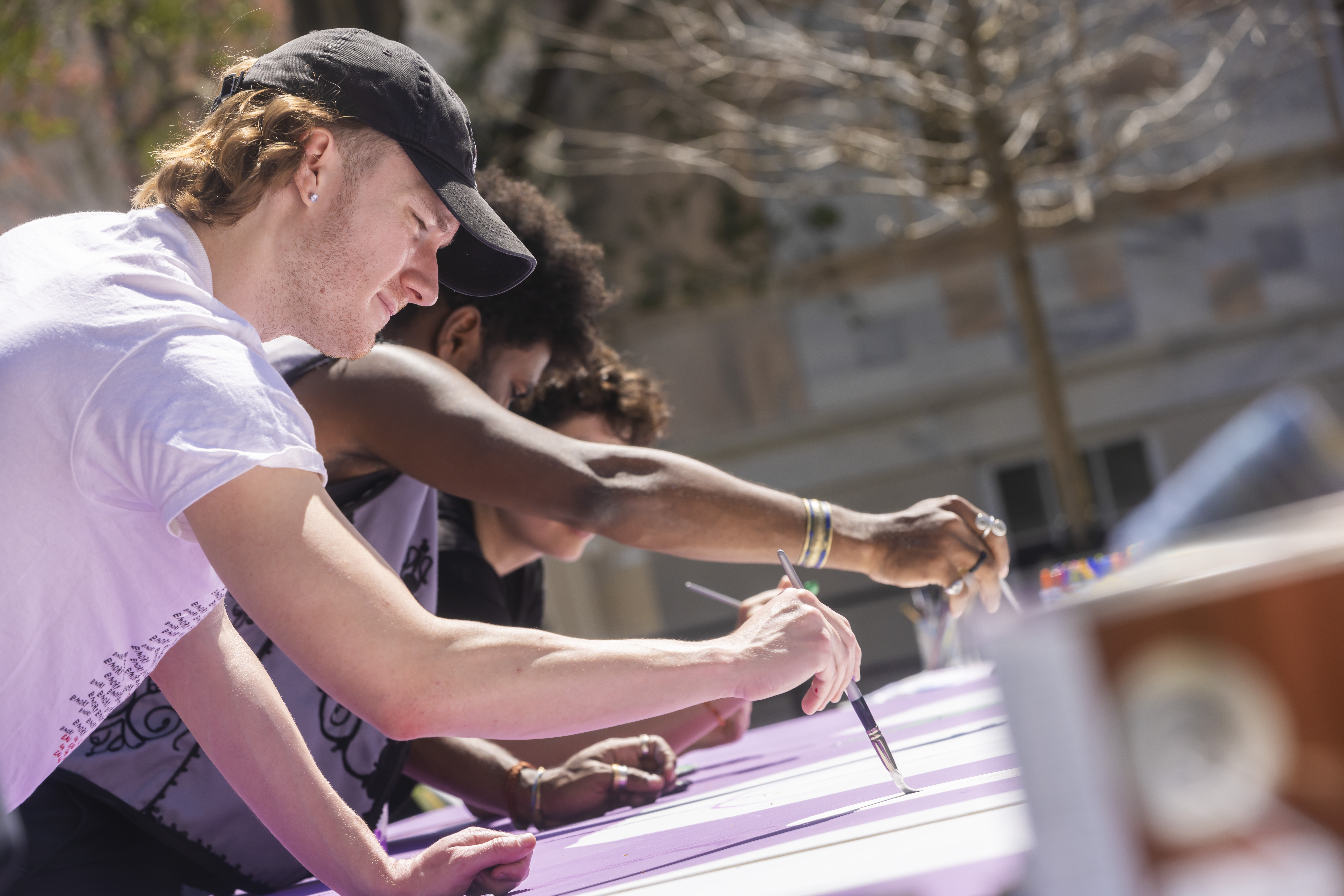 Emory students outside on a sunny day painting a large canvas on a table